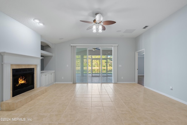 unfurnished living room with built in shelves, ceiling fan, a tile fireplace, light tile patterned floors, and lofted ceiling