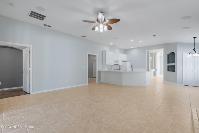 unfurnished living room with sink, ceiling fan with notable chandelier, and light tile patterned flooring