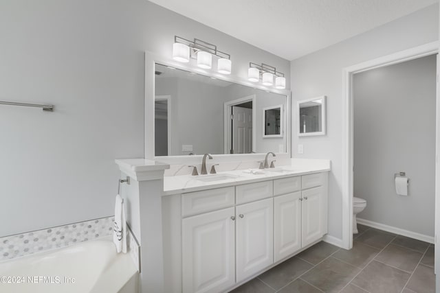 bathroom with tile patterned floors, a bathtub, vanity, a textured ceiling, and toilet