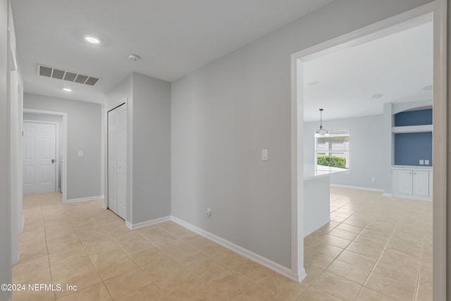 hall with light tile patterned floors and a chandelier