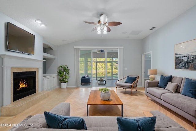 living room featuring a tiled fireplace, vaulted ceiling, ceiling fan, built in features, and light parquet flooring