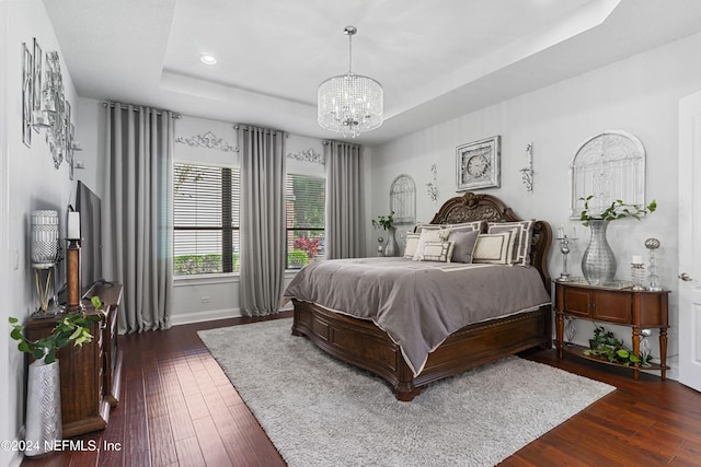 bedroom featuring a tray ceiling, dark hardwood / wood-style floors, and an inviting chandelier