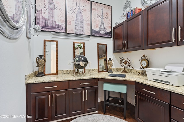 kitchen with built in desk, dark hardwood / wood-style floors, and light stone counters