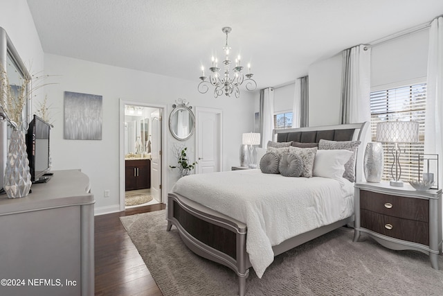 bedroom with ensuite bathroom, dark hardwood / wood-style flooring, and an inviting chandelier