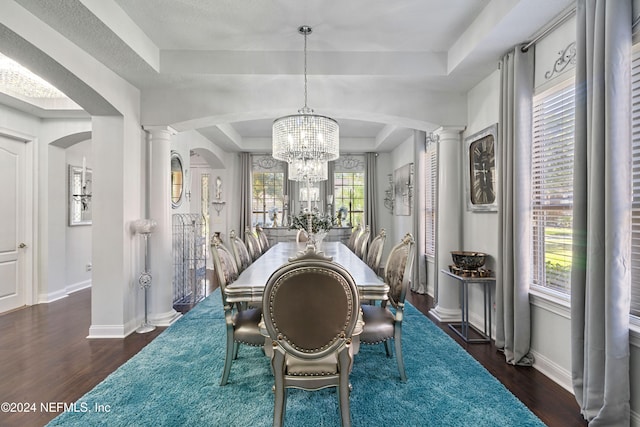 dining area with a raised ceiling, dark wood-type flooring, and a notable chandelier