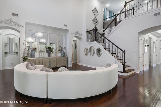 living room with wood-type flooring, a towering ceiling, and a notable chandelier