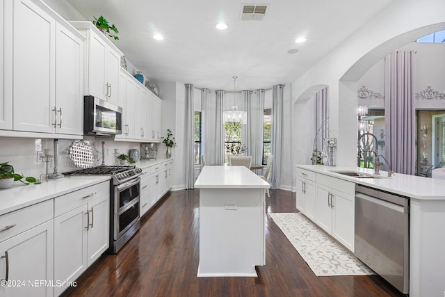 kitchen with a kitchen island, white cabinetry, stainless steel appliances, and dark wood-type flooring