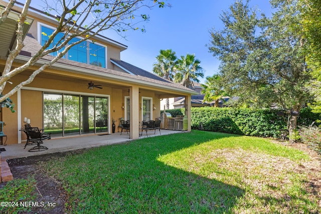 back of house with ceiling fan, a yard, and a patio