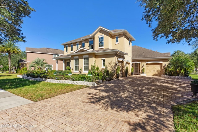 view of front of property with stucco siding, decorative driveway, a front yard, and an attached garage