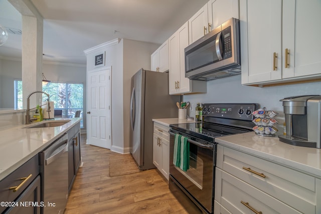 kitchen with sink, light wood-type flooring, appliances with stainless steel finishes, light stone counters, and white cabinetry