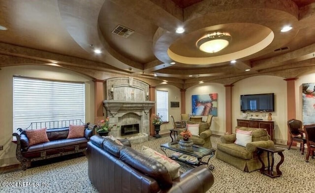 living room with a raised ceiling and a tiled fireplace