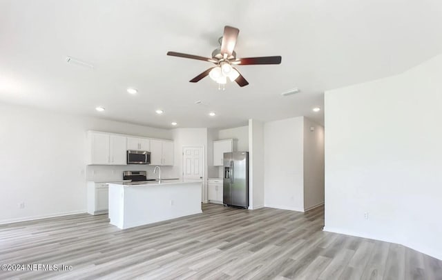 kitchen with ceiling fan, an island with sink, appliances with stainless steel finishes, light hardwood / wood-style floors, and white cabinetry