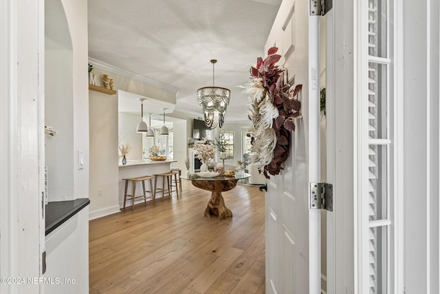 415 N Ocean Grande Dr Unit 101, Ponte Vedra Beach, FL 32082 - corridor featuring light wood-type flooring, crown molding, a chandelier, baseboards, and a textured ceiling