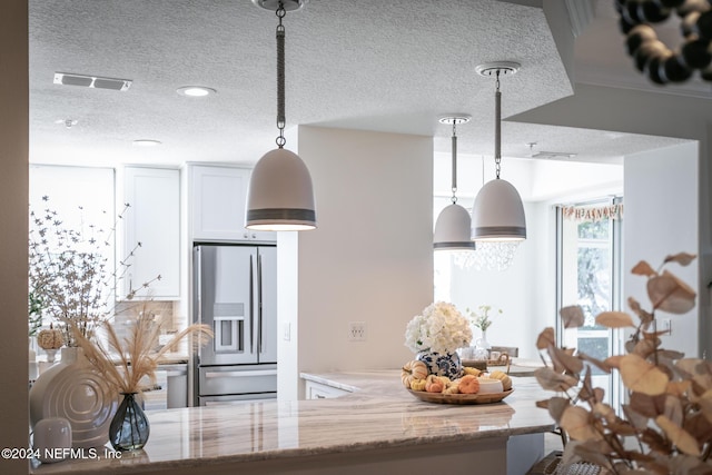 415 N Ocean Grande Dr Unit 101, Ponte Vedra Beach, FL 32082 - kitchen with stainless steel fridge with ice dispenser, a textured ceiling, light stone countertops, pendant lighting, and white cabinets