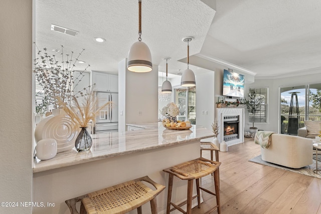 415 N Ocean Grande Dr Unit 101, Ponte Vedra Beach, FL 32082 - kitchen featuring light wood-style floors, open floor plan, ornamental molding, a lit fireplace, and light stone counters