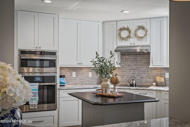 415 N Ocean Grande Dr Unit 101, Ponte Vedra Beach, FL 32082 - kitchen featuring double oven, under cabinet range hood, a textured ceiling, black electric stovetop, and tasteful backsplash