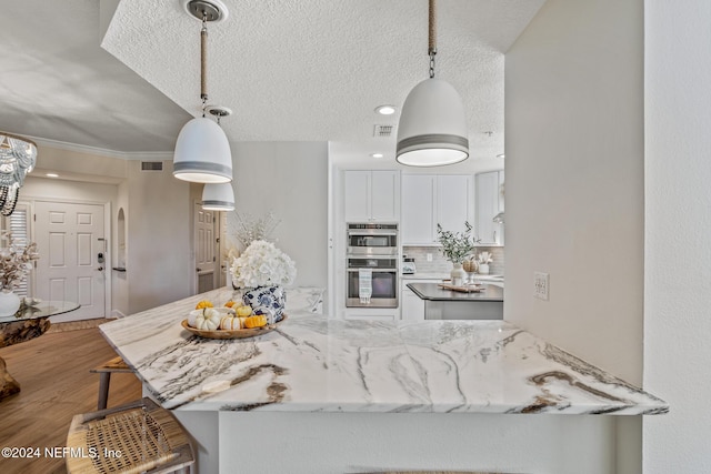 415 N Ocean Grande Dr Unit 101, Ponte Vedra Beach, FL 32082 - kitchen with double oven, white cabinets, wood finished floors, a kitchen bar, and tasteful backsplash