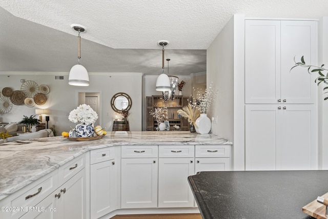 415 N Ocean Grande Dr Unit 101, Ponte Vedra Beach, FL 32082 - kitchen featuring light stone countertops, white cabinetry, pendant lighting, a textured ceiling, and crown molding