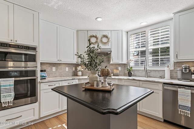 415 N Ocean Grande Dr Unit 101, Ponte Vedra Beach, FL 32082 - kitchen featuring appliances with stainless steel finishes, a sink, decorative backsplash, white cabinetry, and a textured ceiling