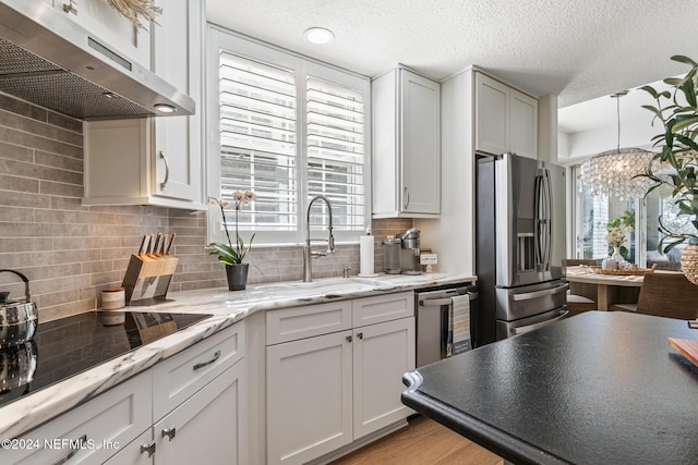 415 N Ocean Grande Dr Unit 101, Ponte Vedra Beach, FL 32082 - kitchen with stainless steel appliances, under cabinet range hood, tasteful backsplash, plenty of natural light, and a textured ceiling