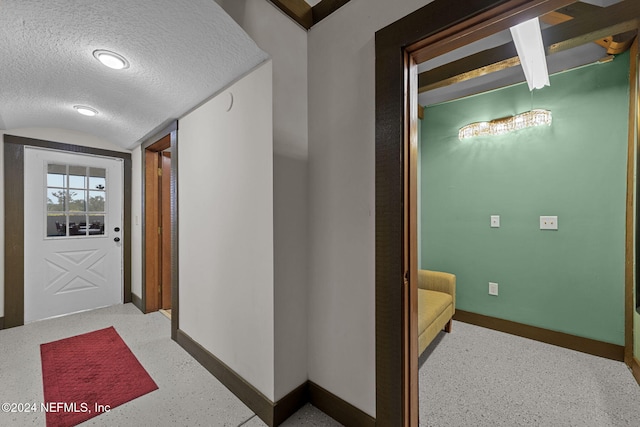 hall featuring lofted ceiling and a textured ceiling