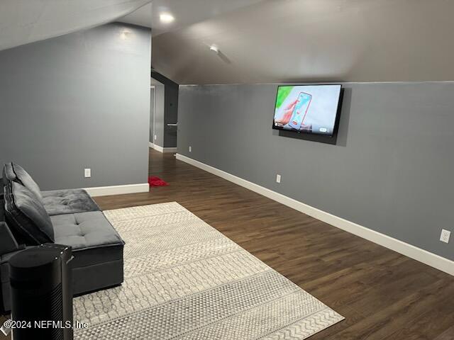 bonus room with dark hardwood / wood-style flooring and vaulted ceiling