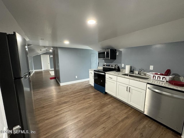 kitchen with appliances with stainless steel finishes, vaulted ceiling, sink, dark hardwood / wood-style floors, and white cabinetry