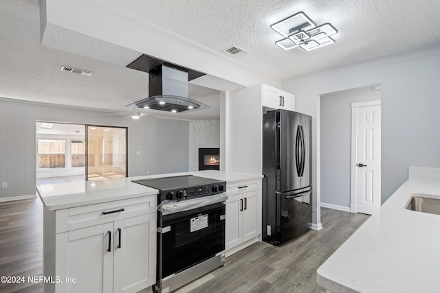 kitchen featuring stainless steel electric range, white cabinetry, exhaust hood, and fridge