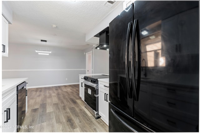 kitchen featuring white cabinetry, wall chimney exhaust hood, light hardwood / wood-style flooring, pendant lighting, and black appliances