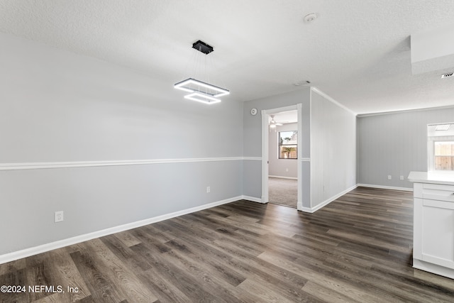 spare room featuring ceiling fan, a healthy amount of sunlight, dark hardwood / wood-style flooring, and a textured ceiling