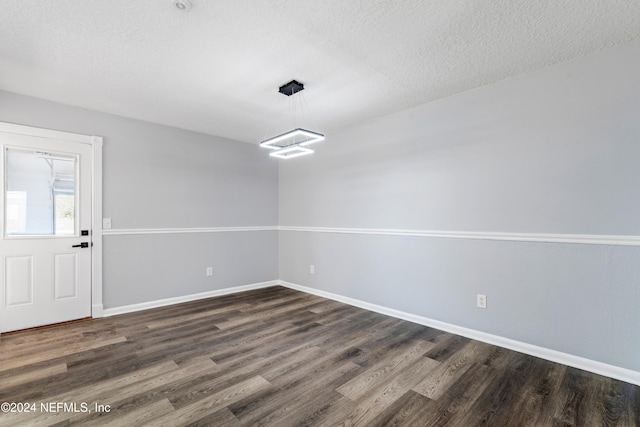 unfurnished dining area with a textured ceiling and dark hardwood / wood-style flooring