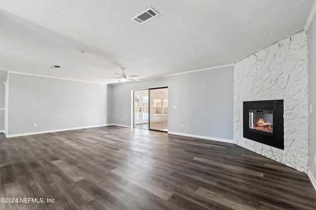 unfurnished living room with dark hardwood / wood-style floors, a large fireplace, ornamental molding, and a textured ceiling