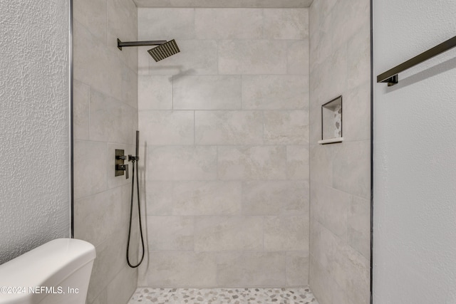 bathroom featuring a tile shower and toilet