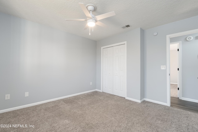 unfurnished bedroom featuring carpet, ceiling fan, a textured ceiling, and a closet