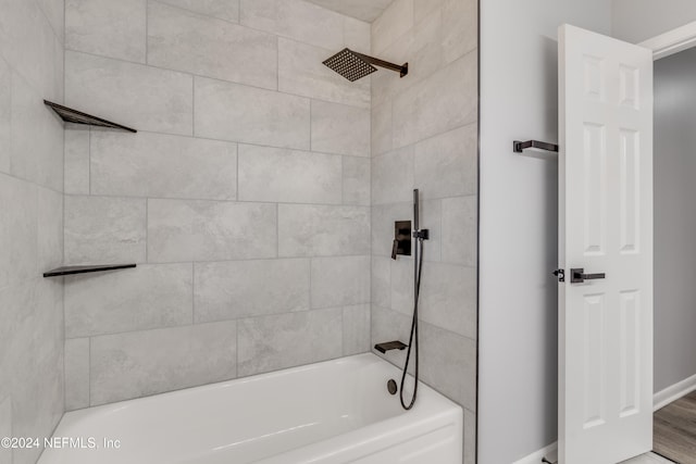 bathroom featuring wood-type flooring and tiled shower / bath