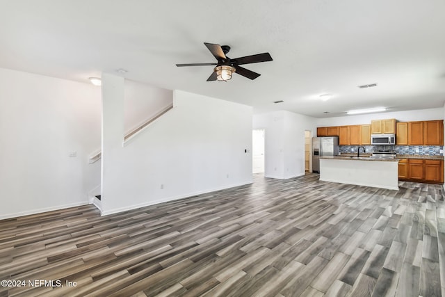 unfurnished living room with ceiling fan, wood-type flooring, and sink