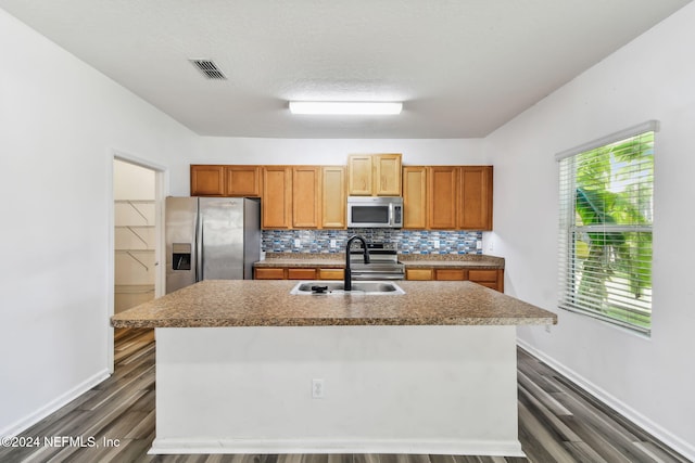 kitchen with a kitchen island with sink, dark wood-type flooring, and stainless steel appliances