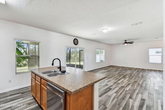 kitchen with hardwood / wood-style floors, dishwasher, sink, and a kitchen island with sink