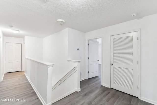 hall with wood-type flooring and a textured ceiling