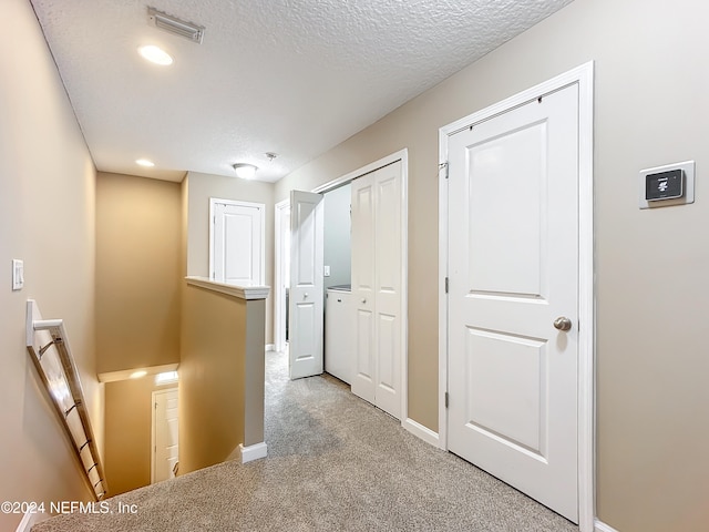 hall featuring a textured ceiling and light carpet