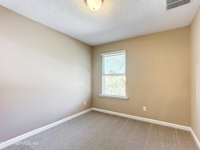 carpeted empty room featuring a textured ceiling