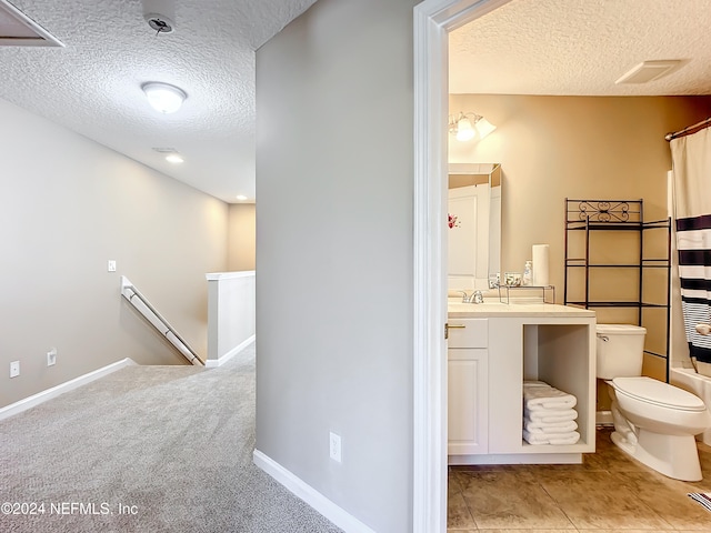 full bathroom featuring shower / bath combination with curtain, vanity, a textured ceiling, tile patterned flooring, and toilet