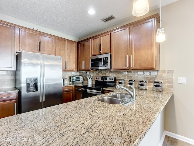 kitchen featuring decorative backsplash, a textured ceiling, stainless steel appliances, sink, and pendant lighting