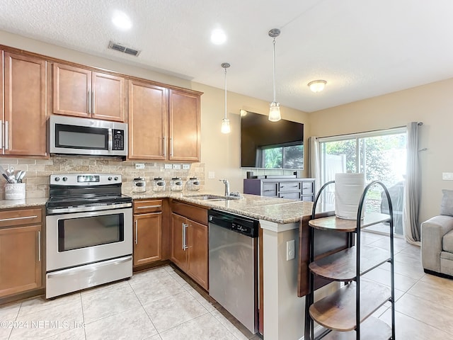 kitchen featuring pendant lighting, sink, decorative backsplash, kitchen peninsula, and stainless steel appliances