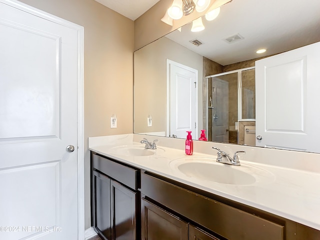 bathroom featuring a shower with door and vanity