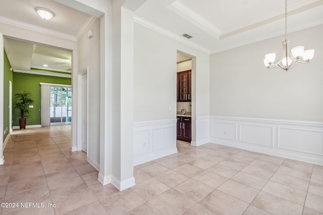 tiled spare room featuring sink, a raised ceiling, crown molding, and an inviting chandelier