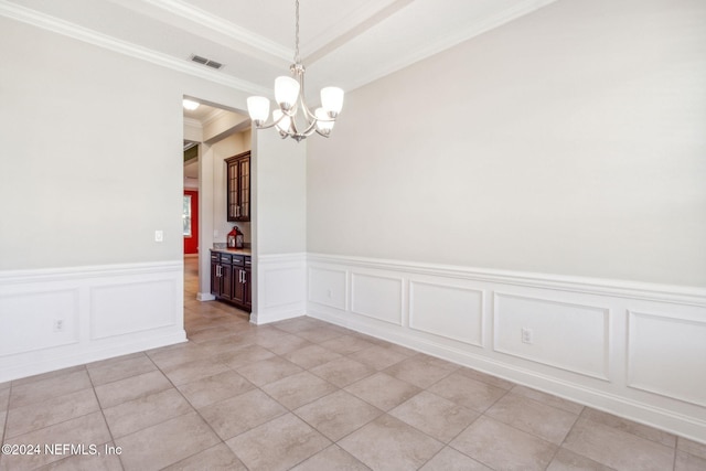 tiled spare room with ornamental molding and an inviting chandelier