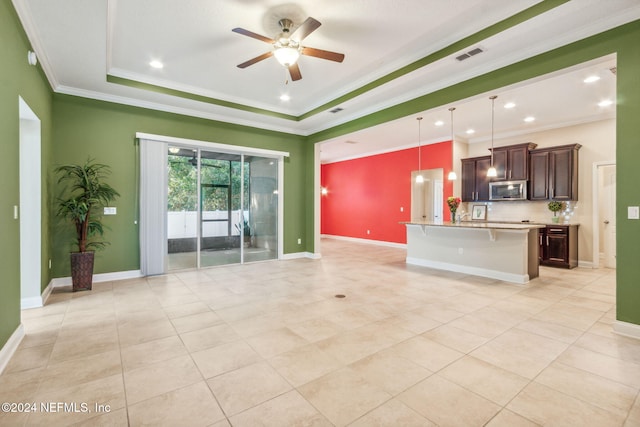 unfurnished living room with a raised ceiling, ceiling fan, crown molding, and light tile patterned floors