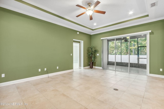 spare room with a tray ceiling, ceiling fan, crown molding, and light tile patterned floors