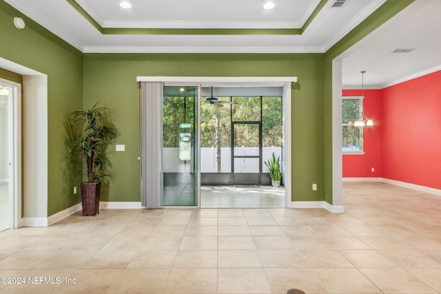 doorway with light tile patterned flooring, crown molding, a tray ceiling, and an inviting chandelier